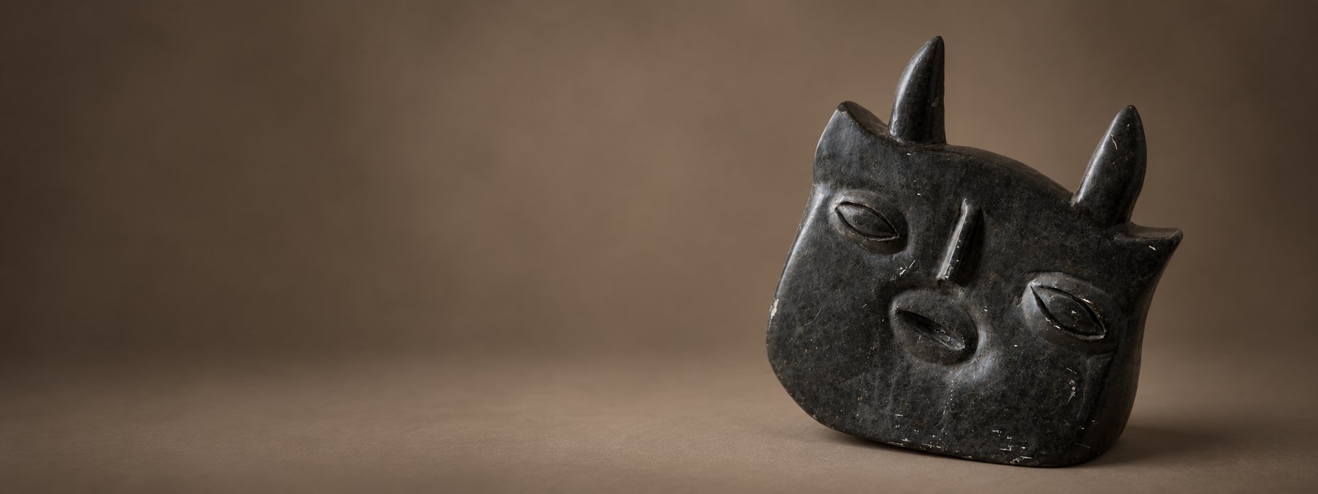 Carved dark stone mask with horns